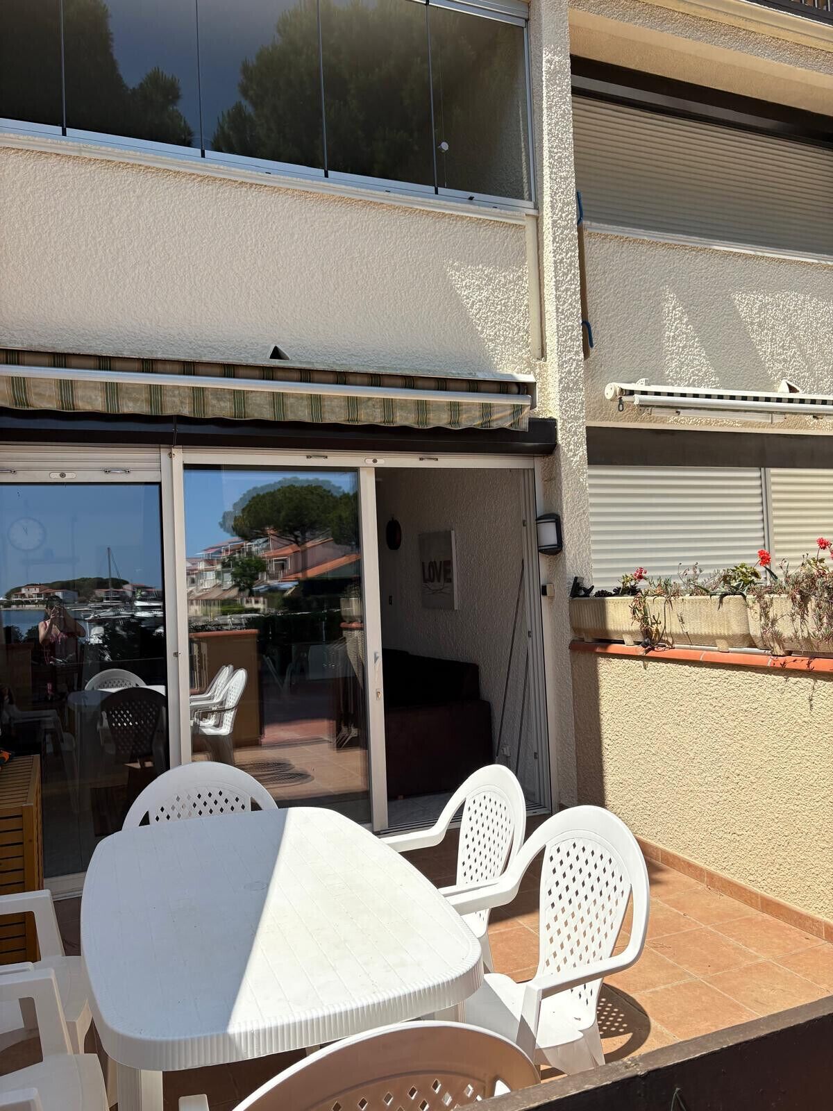 A patio area with a table and chairs, a sliding glass door leading to an indoor space, and a view of the marina.