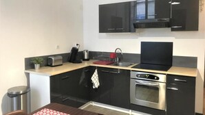 Una cocina compacta con armarios negros, un horno de acero inoxidable y un microondas.