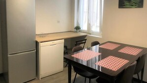 Cocina compacta con refrigerador, lavavajillas y una mesa de comedor con cuatro sillas.