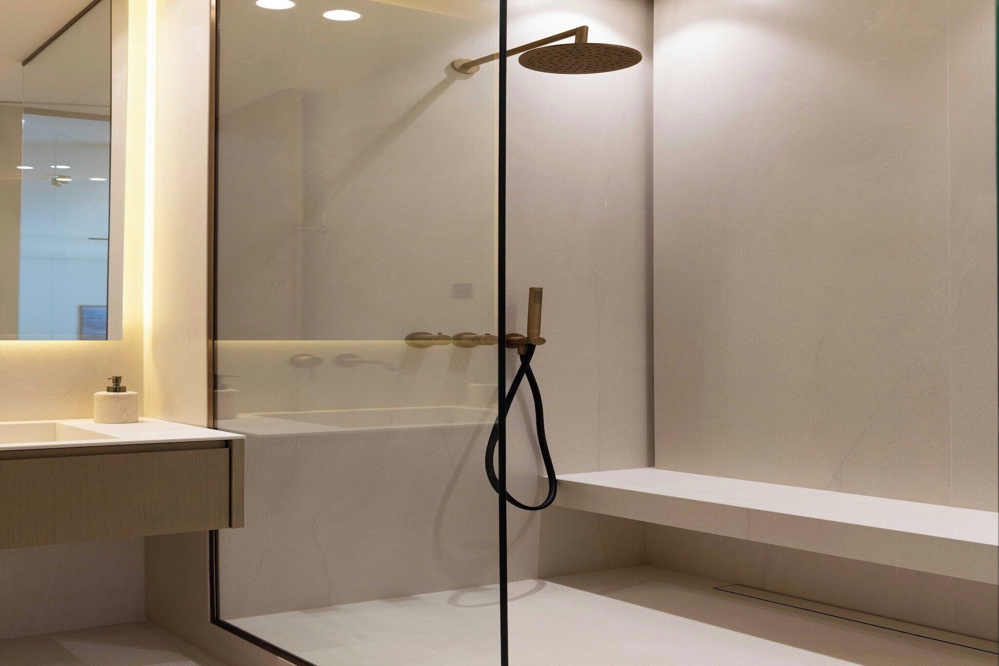 Een moderne badkamer met een douche met glazen wand, een wit wastafelmeubel en een spiegel.