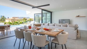 Sala de estar moderna com área de jantar, janelas amplas e vista da cidade.
