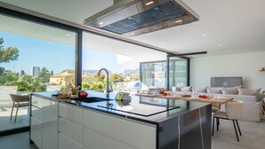 Cozinha moderna com uma ilha grande, área de jantar com sofá e vista para a cidade.