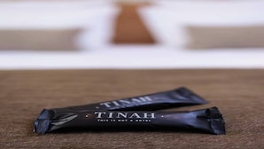 Two black bags labeled "TINAH" on a brown surface with a blurred background.
