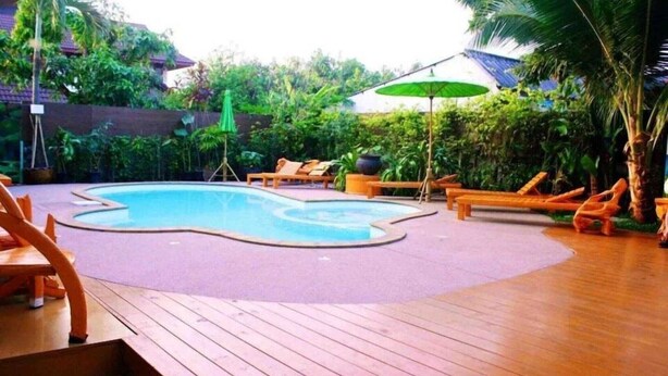 A wooden deck with a pool, surrounded by lounge chairs and umbrellas. - Superior Double Stay | Sleek & Cozy (Chiang Mai)