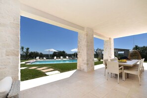 A covered outdoor area with a pool, lounge chairs, and a dining table with chairs. - Villa in Ostuni with 10 bedrooms sleeps 24 (Ostuni)