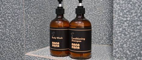 Two bottles of body wash and conditioning shampoo on a shelf against a speckled tile wall.