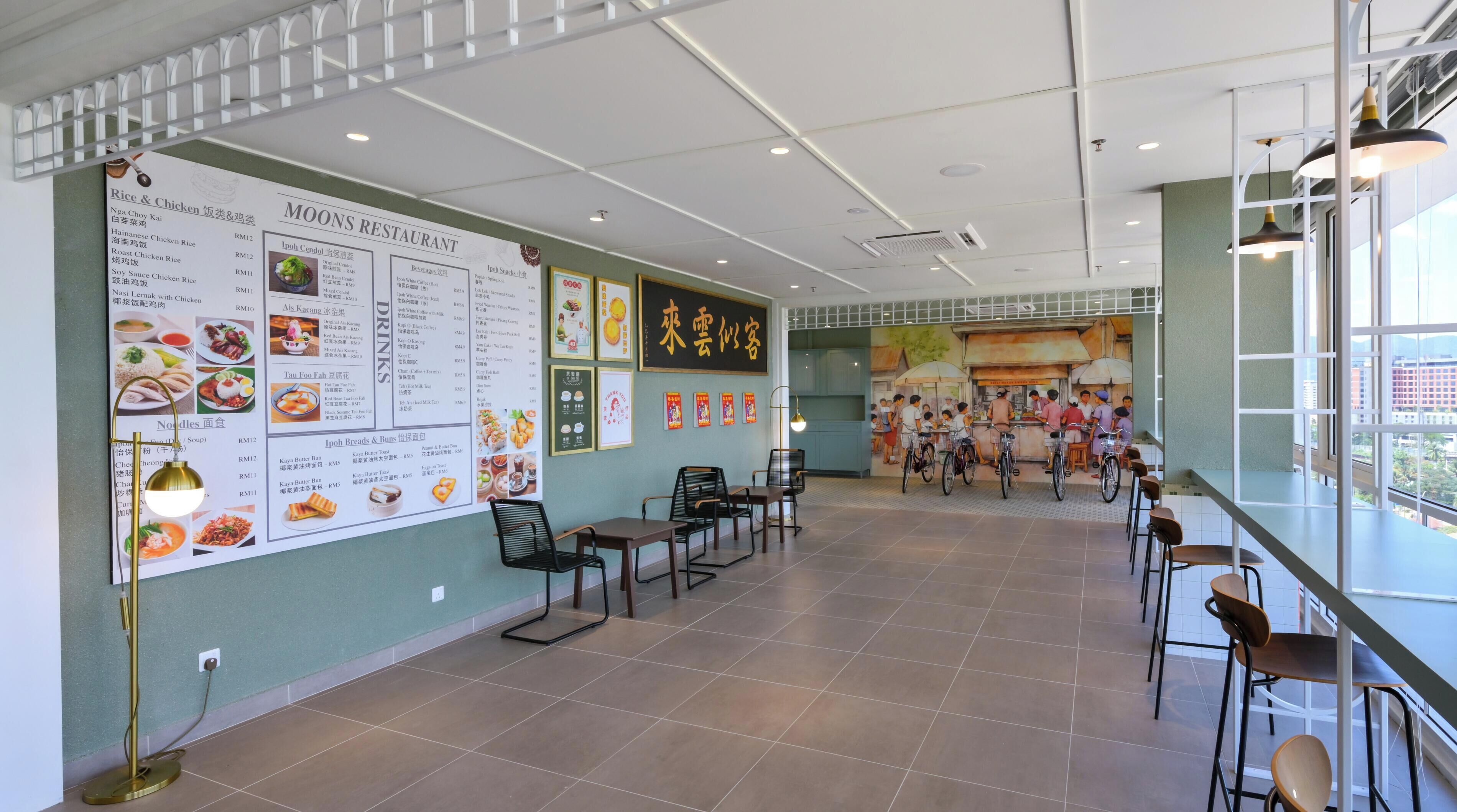 A spacious restaurant interior with a high ceiling, a menu board on the left, and a seating area with tables and chairs.