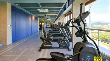 Una palestra con tapis roulant ed ellittiche, una parete blu e una finestra con vista sulla città.