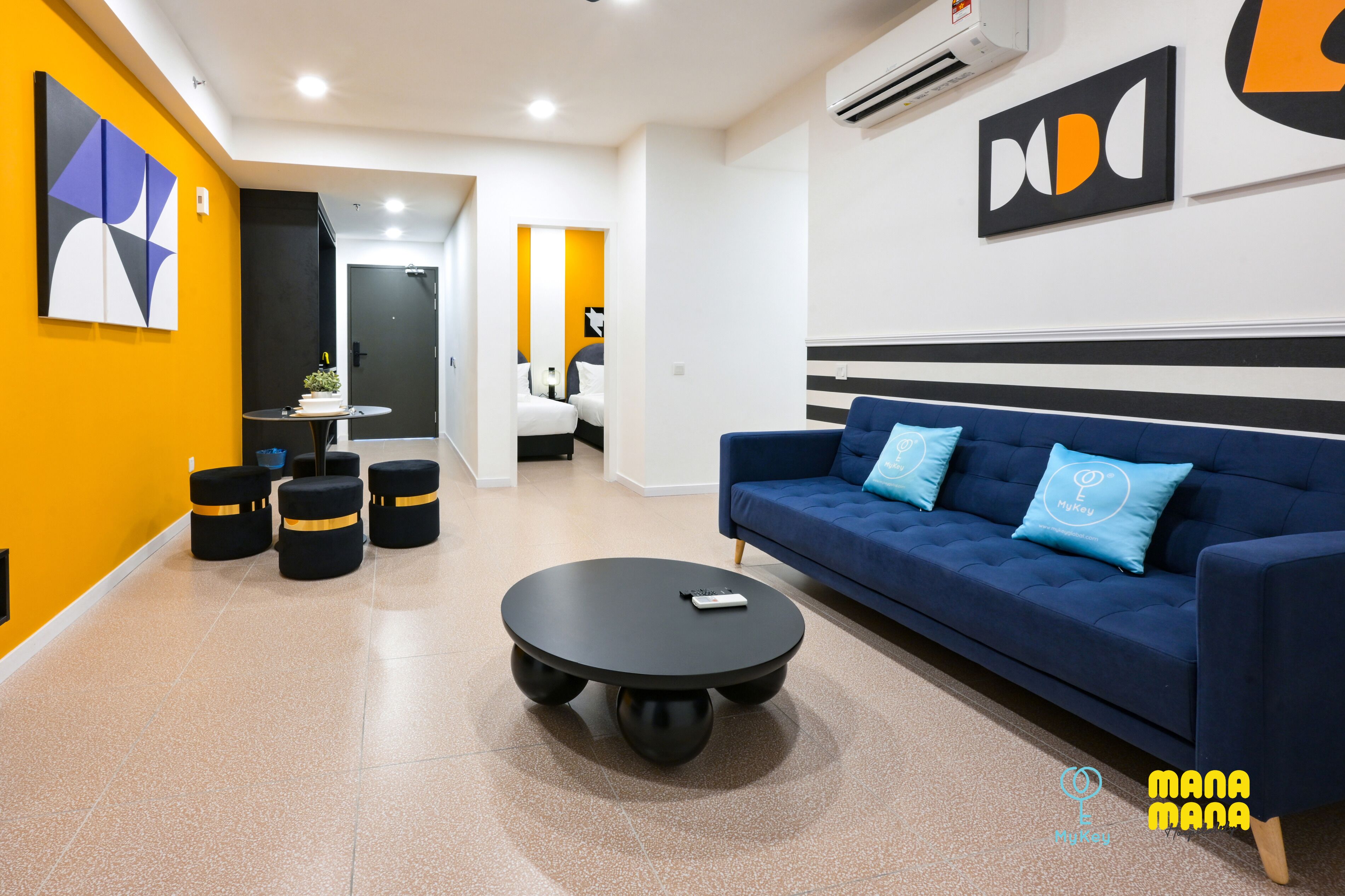 A modern hotel lobby with a blue sofa, a round black coffee table, and a yellow accent wall.