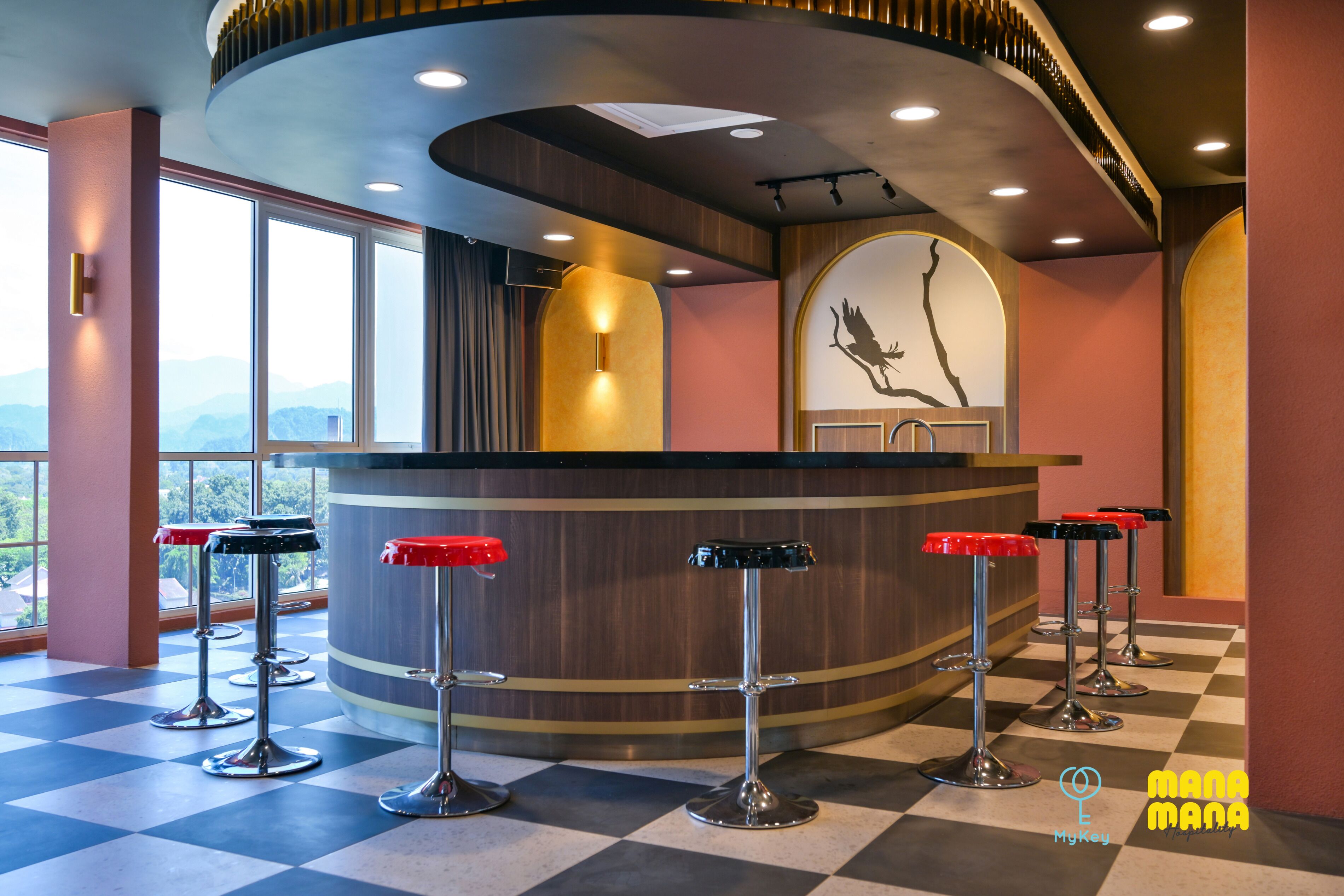 A bar area with a curved counter and four stools, large windows, and a mural on the wall.