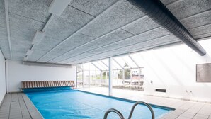 An indoor swimming pool with clear glass walls, a bench, and a tiled floor. - "Nis" - 900m from the sea by Interhome (Blokhus)