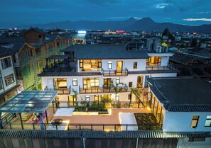 A modern multi-story building with a rooftop garden and a large glass conservatory. - Togruo Ge Qi Shi Inn (Lijiang)