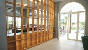 Un espace d’accueil avec un séparateur en bois, un comptoir de réception et une vue sur l’extérieur.