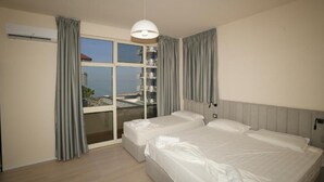 Une chambre d’hôtel avec deux lits, une grande fenêtre avec des rideaux, un luminaire au plafond et un appareil de climatisation.