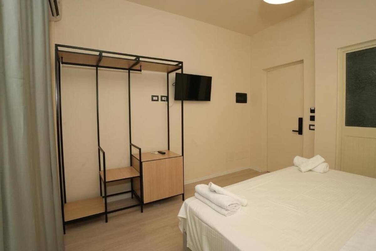 Una camera da letto con un letto, un armadio, una scrivania e una TV montata a parete.