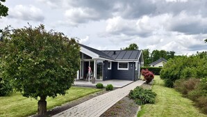 Une maison moderne avec une allée pavée, un grand arbre et une pelouse bien entretenue.