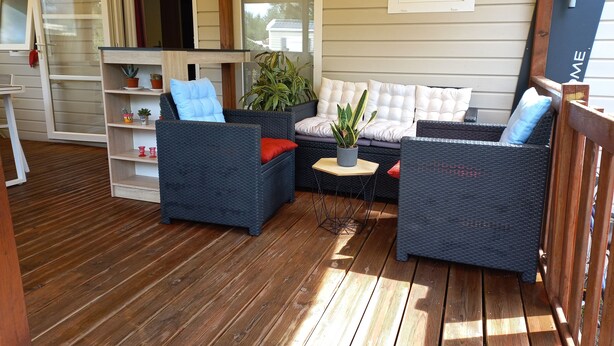 A covered outdoor seating area with wicker furniture and potted plants.