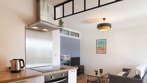 A modern kitchen with a built-in oven and a coffee maker. There is a grey sofa and a small table with a plant. - Arcachon Marines by Interhome (Arcachon)