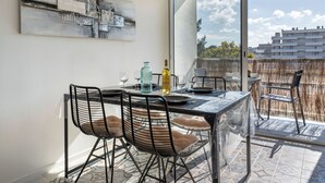 A dining area with a table, chairs, and a view of buildings through large windows. - Arcachon Marines by Interhome (Arcachon)
