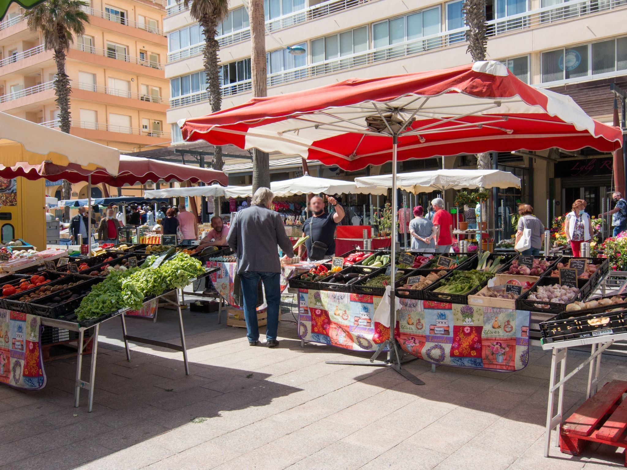 An outdoor market with various stalls selling fresh produce and flowers.