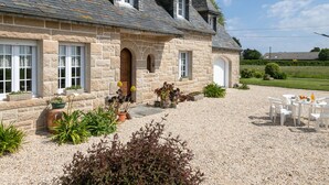 A stone house with a gravel driveway, outdoor seating, and a garden. - Ti Breizh by Interhome (Guimaëc)