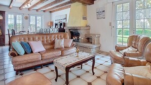 A spacious living room with a leather sofa, a coffee table, and a fireplace. - Ti Breizh by Interhome (Guimaëc)