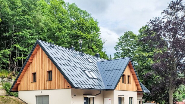 Et moderne hus i to etager med skråt tag, træfacade og stensokkel.