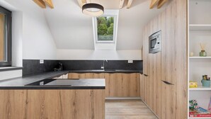 Une cuisine moderne avec des meubles en bois, un plan de travail noir et une lucarne au-dessus de l’évier.