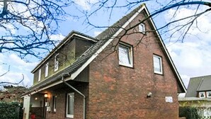 A two-story brick house with a sloped roof, a front porch, and a small front yard. - Fewo 1 in ruhigem Haus by Interhome (Sylt)