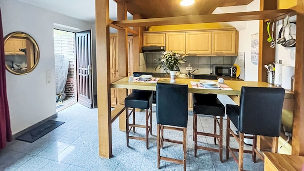 Una cocina compacta con armarios de madera, una isla central con taburetes de bar, microondas y refrigerador.