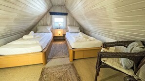A cozy attic bedroom with two beds, a window, and a wicker chair. - Fewo 4 in ruhigem Haus by Interhome (Sylt)