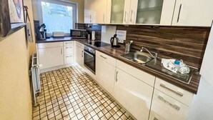 A modern kitchen with white cabinets, a stainless steel sink, and a tiled floor. - Vacation home Tinnum by Interhome (Sylt)