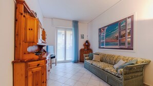 Un salon comprenant un meuble en bois, un canapé, un tableau et une porte-fenêtre coulissante donnant sur un espace extérieur.