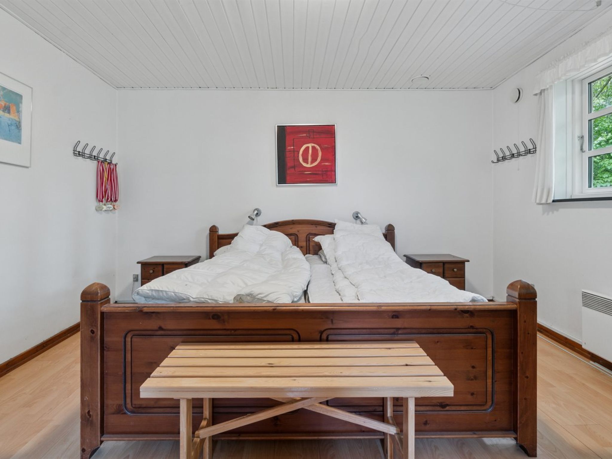 A neatly made bed with a wooden headboard, a bedside table, and a small bedside lamp.