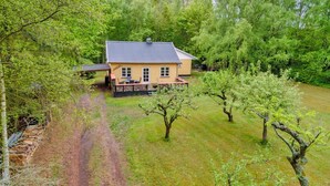 Une maison de plain-pied, dotée d’un toit en tuiles, entourée d’une pelouse bien entretenue et d’arbres.