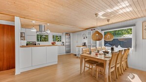 A modern kitchen with wooden cabinets, a central island, and pendant lighting. - "Eine" -  from the sea by Interhome (Hals)