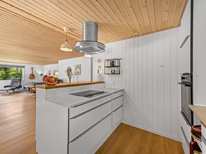 Una cocina moderna con armarios blancos, techo de madera y horno empotrado.