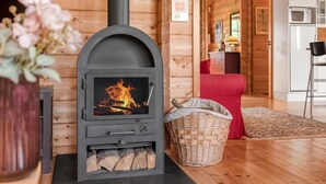 Een gezellig chaletinterieur met een houtkachel, een rode bank en een keukenhoek.