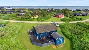 A coastal residential area with houses, a blue building with a deck, and a view of the sea.