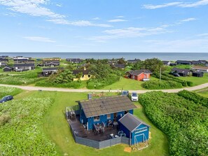 Ein Küstenwohngebiet mit Häusern, einem blauen Gebäude mit Terrasse und Blick aufs Meer.