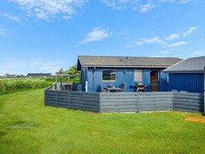 Ein blaues Gebäude mit einem von einer Ziegelmauer umgebenen Patio, einem Tisch und Stühlen.
