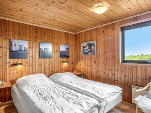 Ein Zimmer mit Holzwänden, zwei Betten, Wandlampen und gerahmten Bildern.