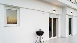 Un bâtiment moderne avec une façade blanche, une grande fenêtre et un barbecue.