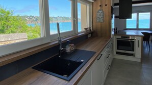 Une cuisine moderne dotée de grandes fenêtres offrant une vue panoramique sur la côte.