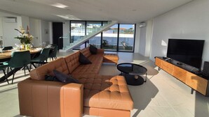 Een moderne woonkamer met een leren bank, een eethoek en een televisie.
