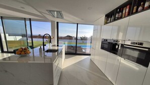 Een moderne keuken met grote ramen, een centraal eiland en inbouwapparatuur.