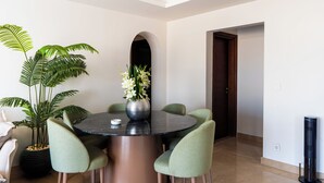 A dining area with a round table, four chairs, a potted plant, and a vase of flowers. - Easy Rental/ Serviced Apartment In CFC New Cairo (NEW Cairo Governorate)