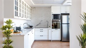 A modern kitchen with white cabinets, a marble backsplash, and stainless steel appliances. - Easy Rental/ Serviced Apartment In CFC New Cairo (NEW Cairo Governorate)