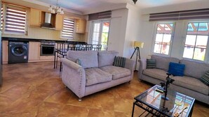A spacious living area with two sofas, a coffee table, and a kitchen in the background. - 6-bedroom villa in beautiful Ölüdeniz with WiFi, AC (Ölüdeniz)