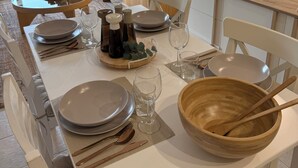 Zona de dinar amb una taula preparada per a quatre, incloent plats, gots i cubiertos.